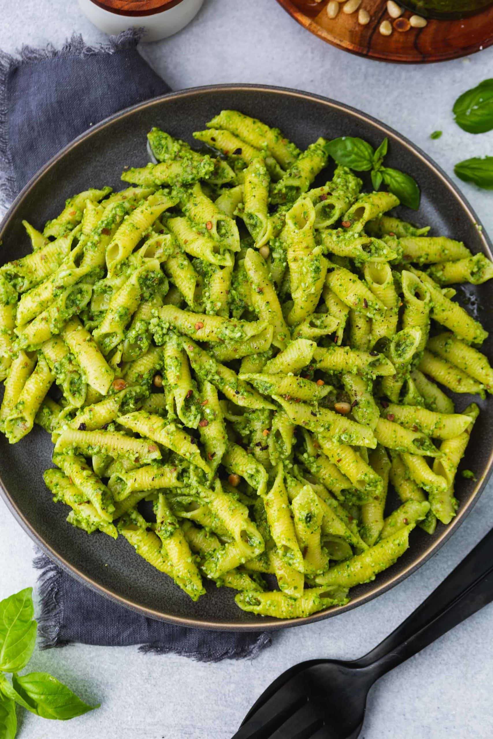 a close up photo of a plate full of bright green pesto covered penne pasta.