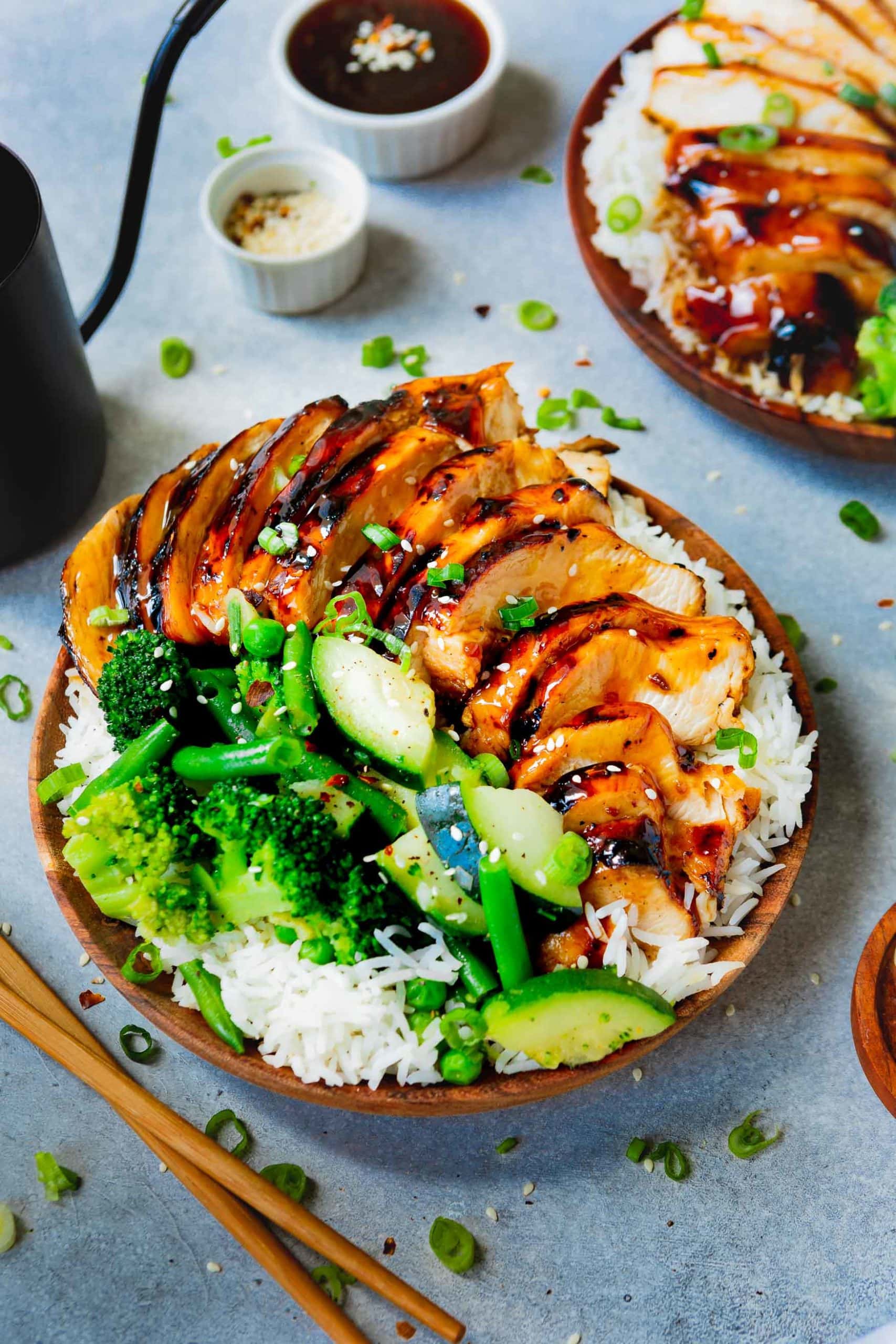 a photo of a plate of rice covered with teriyaki chicken and steamed broccoli, green beans and zucchini.