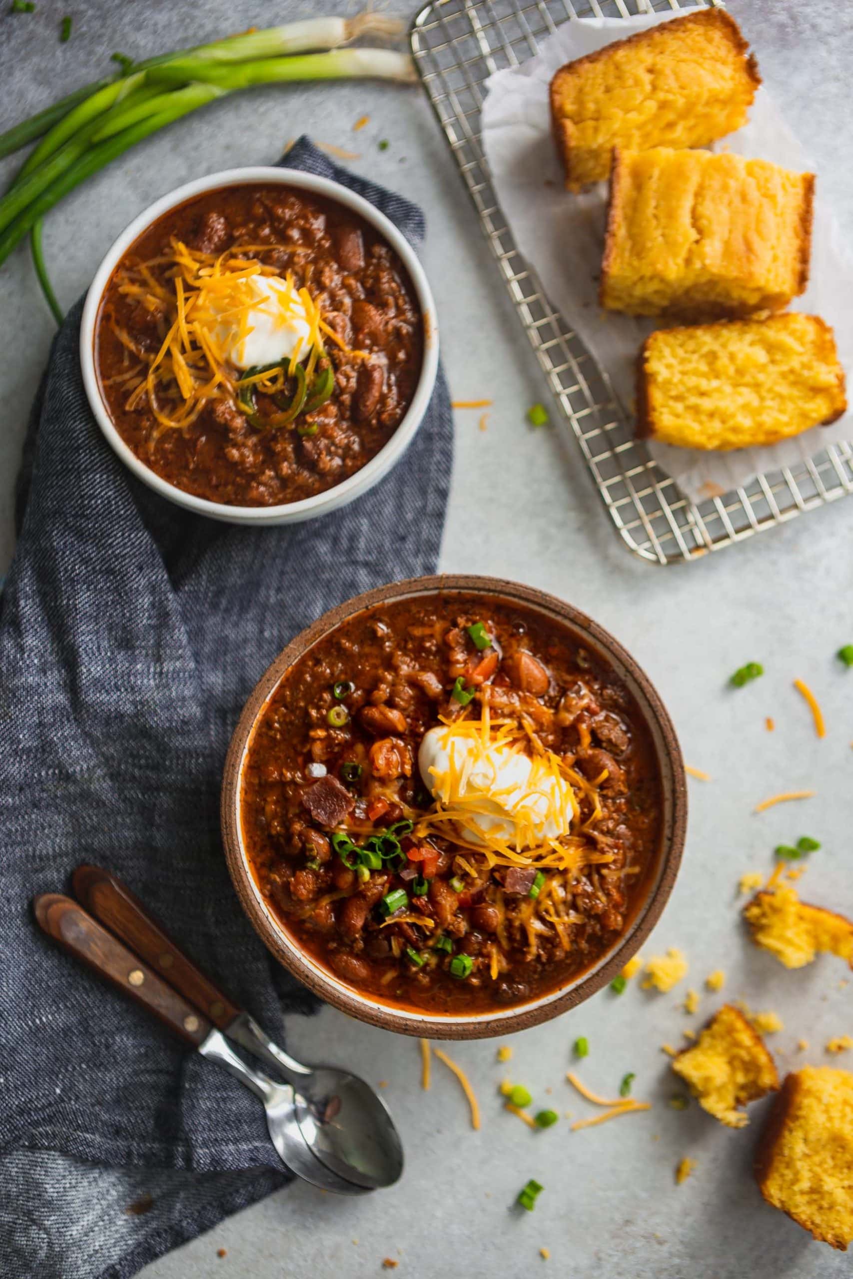 Two bowls of the best chili. The chili is made with beans, ground beef and herbs and spices. It is topped with sour cream and grated cheese.