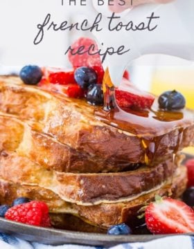 A pile of French toast with maple syrup and berries on top